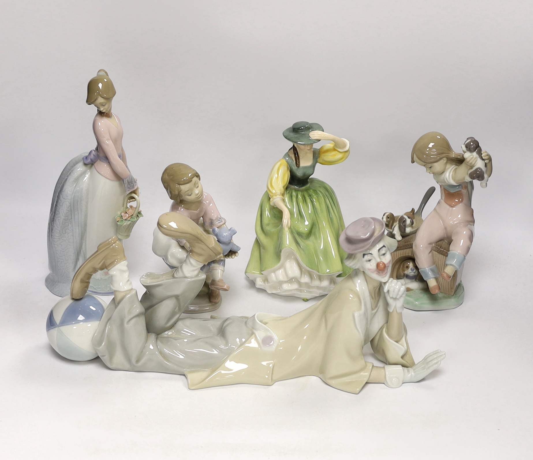 A Lladro recumbent clown, three smaller Lladro figures and a Royal Doulton Buttercup figure, clown 37.7cm wide (5)